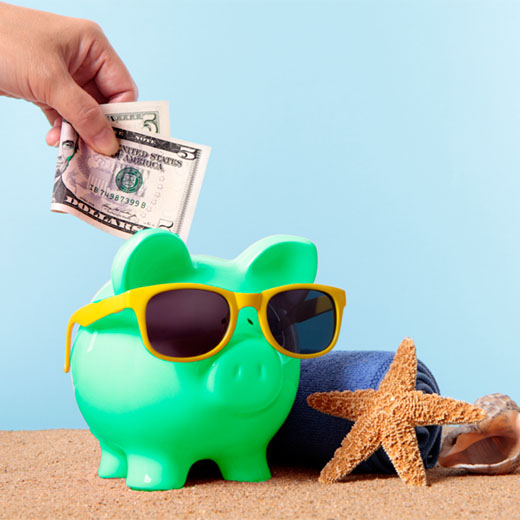 Money being put into a piggy bank on the beach